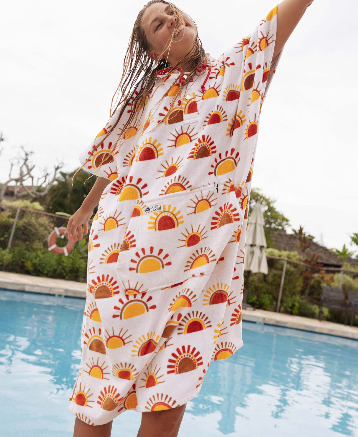 Woman wearing a sun patterned towel poncho by a pool