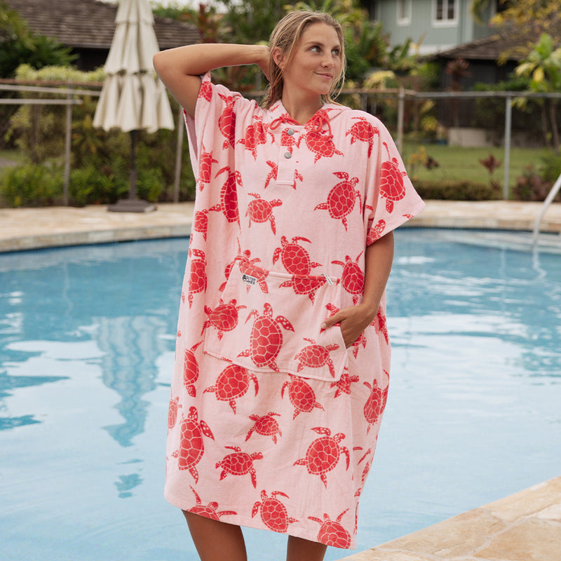 Woman wearing a pink towel with dark pink turtle pattern by a pool