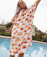Woman wearing a sun patterned towel poncho by a pool