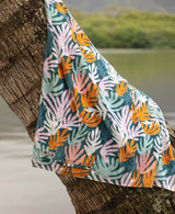 Colorful  coral patterned towel draped over a palm tree with a blurred natural background