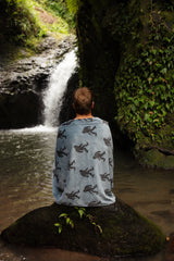 Man by a waterfall with Bigfoot-print towel around his shoulders.