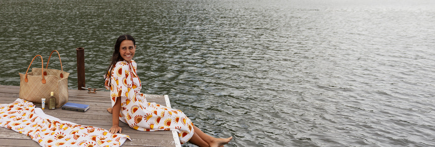 Woman on a dock in sun-print towel poncho with matching towel and bag