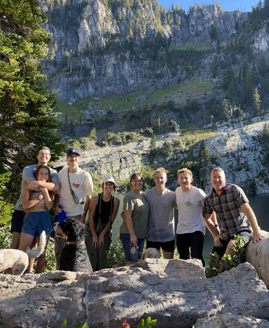 Group of people posing for a photo in a mountainous area with a lake in the background.