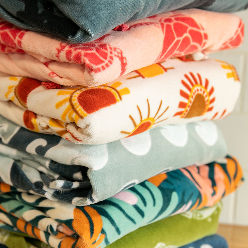 Stack of colorful folded towel ponchos with various patterns