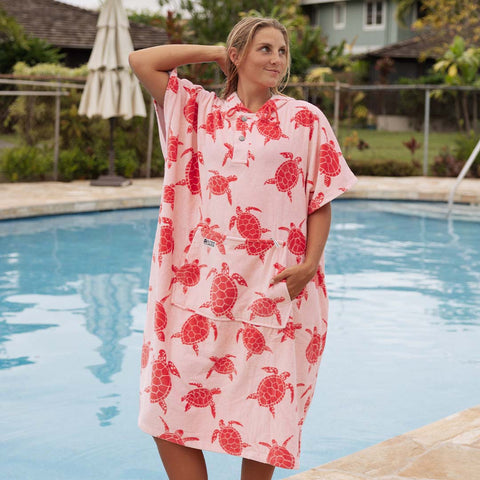 Woman wearing a pink towel poncho with dark pink turtle pattern by a pool